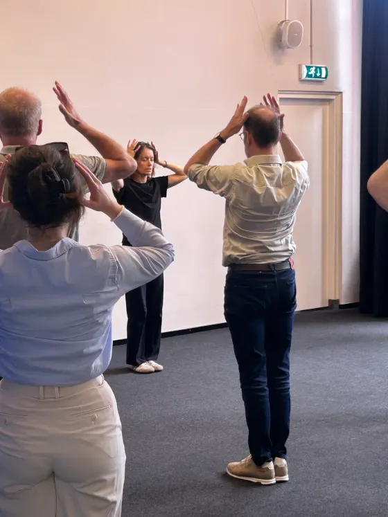 Deelnemers doen een rustige bewegingsoefening tijdens de workshop Chi Neng Qigong