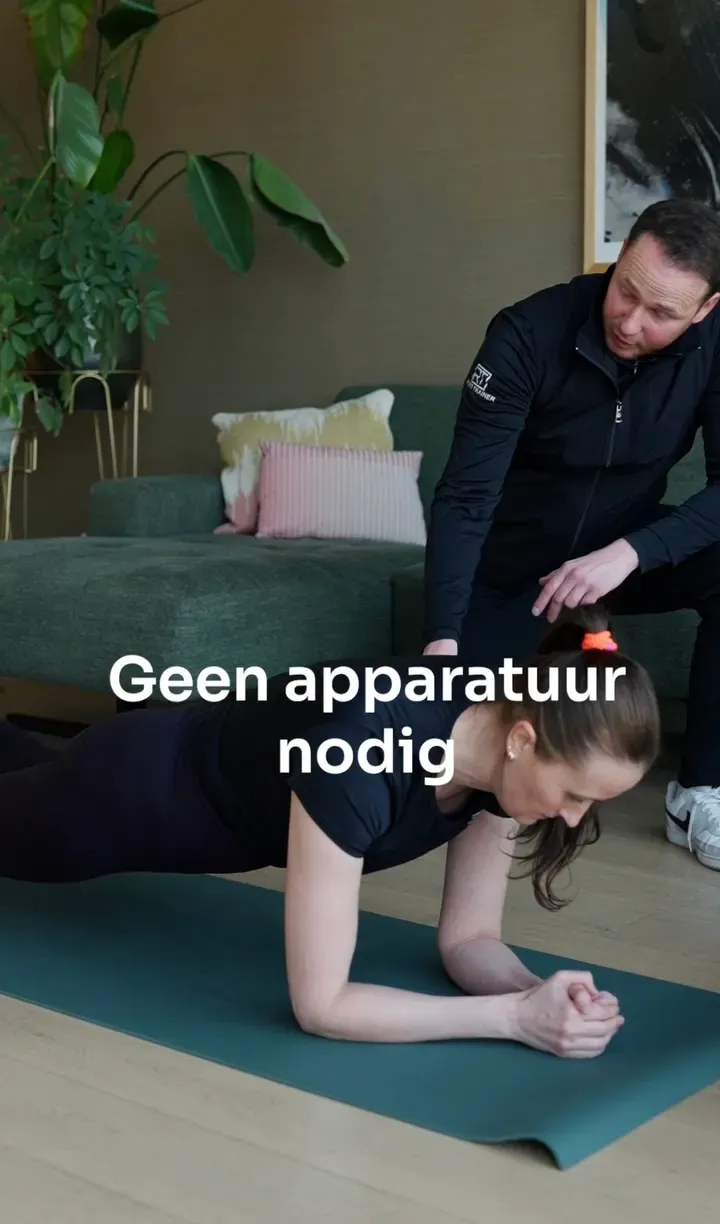 Een klant doet een plank op een mat in de woonkamer terwijl de personal trainer haar houding begeleidt.